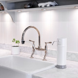 Pearl water filtration system has a small, but mighty footprint,  in a modern white kitchen countertop with farm sink and small plant.