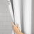 Nebia Shower Curtain in a gray bathroom with a hand opening the curtain